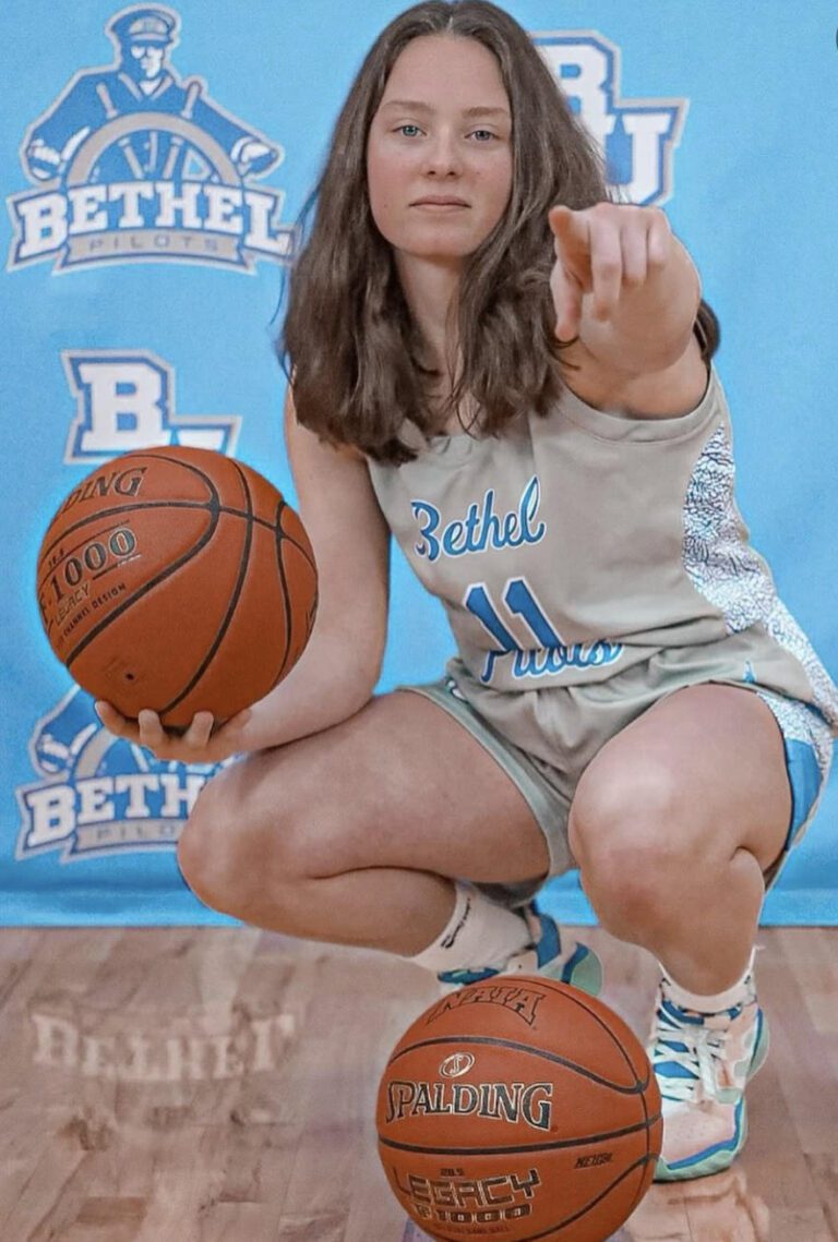 girl holding basketball pointing at camera